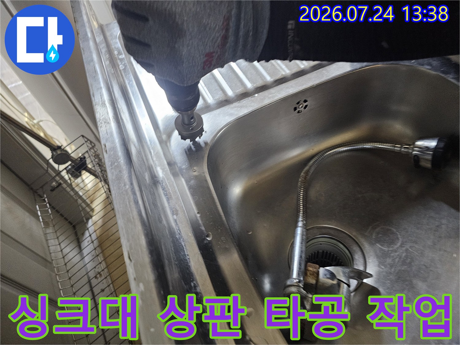 회색 장갑을 낀 작업자가 전동 드릴로 싱크대 스테인리스 상판 부위를 정밀하게 타공하는 모습