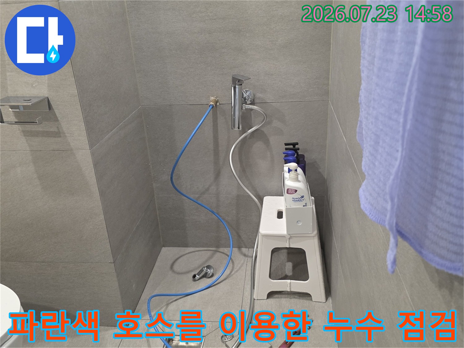 화장실 내부에 설치된 수전과 연결된 파란색 측정용 호스와 주변 공구들