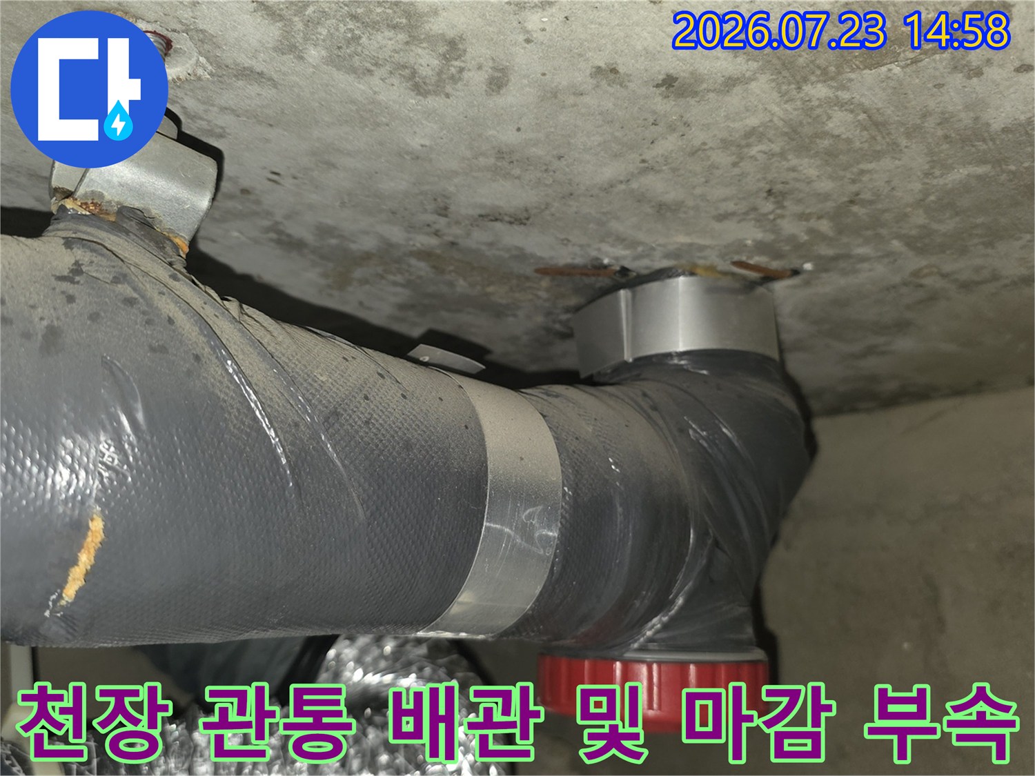 회색 보온재로 감싸진 배관이 천장을 통과해 빨간색 캡으로 마무리된 모습의 사진