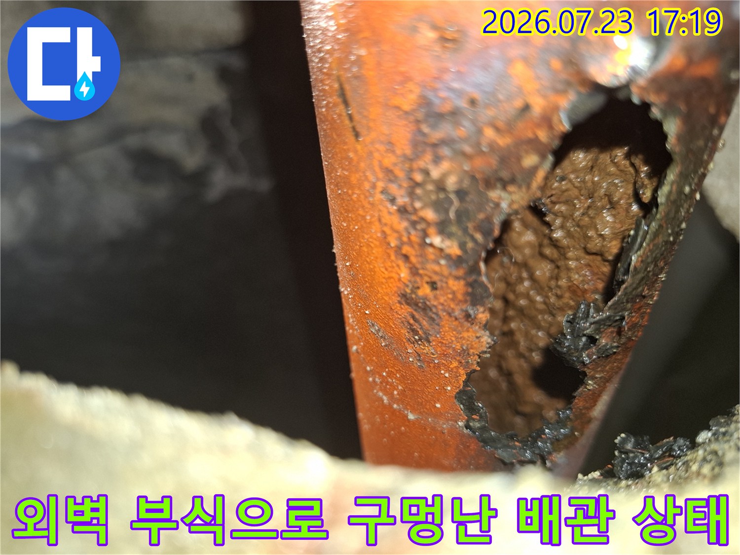 심하게 부식되어 거칠게 뚫려 있는 오렌지색 배관의 누수 지점 모습