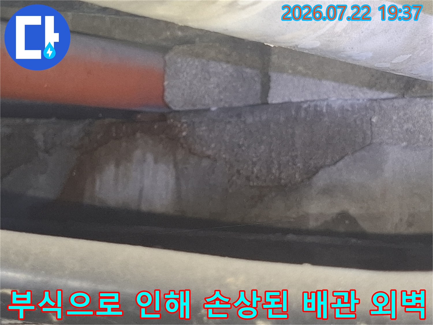 주황색 배관 표면이 부식되어 갈라지고 거칠어진 누수 지점의 모습