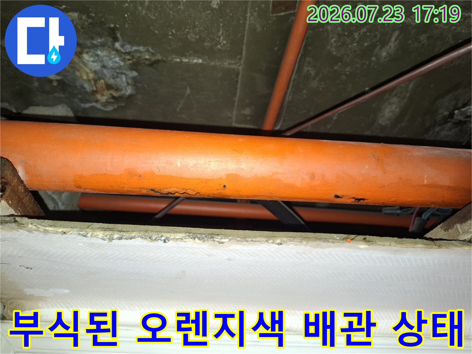 천장에 설치된 노란빛의 오렌지색 배관 표면이 부식되어 거칠어진 모습