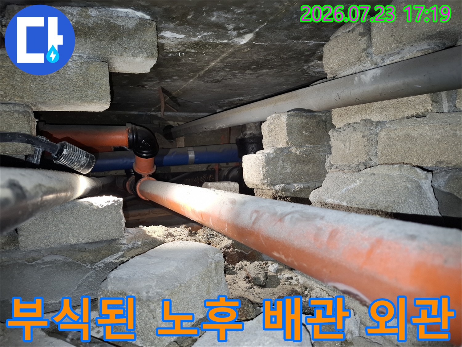 콘크리트 벽체 사이로 배치된 주황색 배관과 푸른색 배관의 연결 모습
