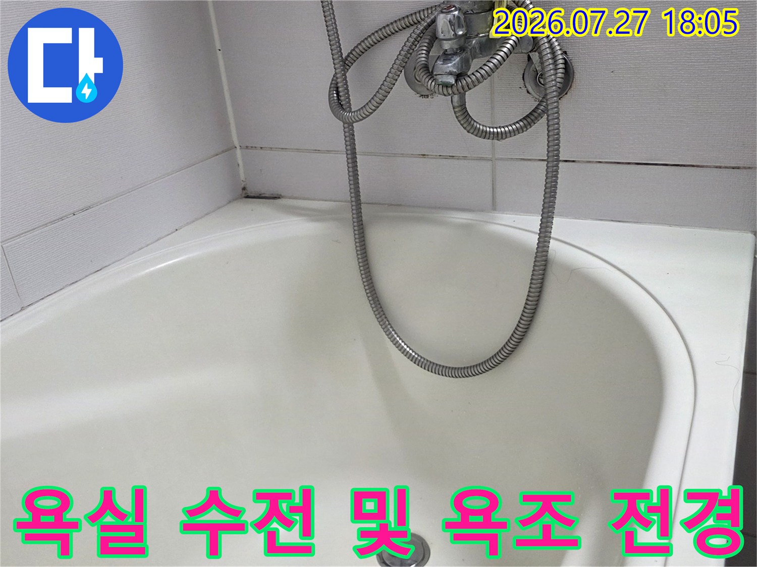 은색 샤워 호스가 늘어져 있는 흰색 욕조-벽면 타일의 경계 부위 사진
