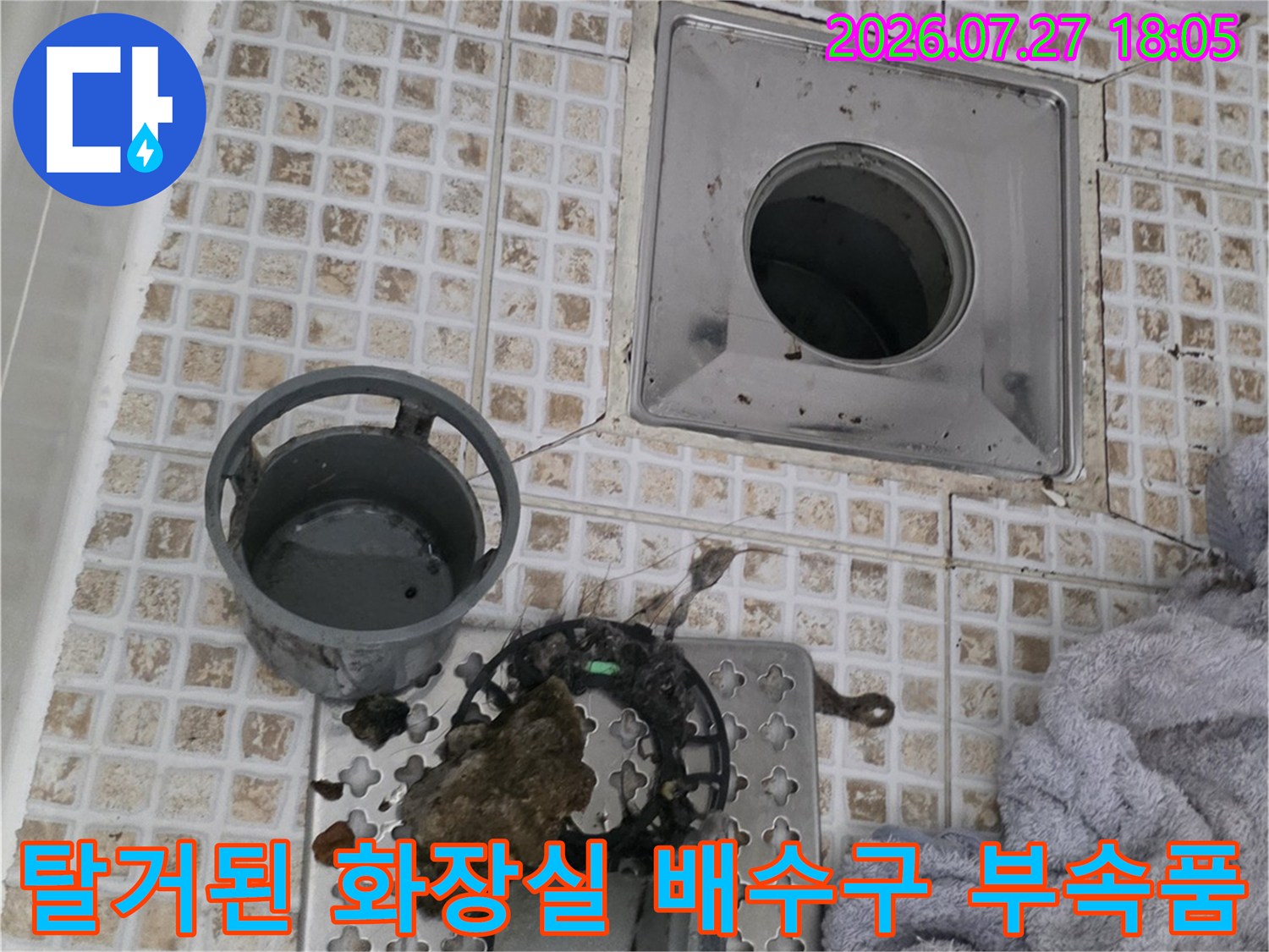타일 바닥 위에 놓인 오염된 유가 거름망과 플라스틱 트랩 그리고 드러난 하수관 입구