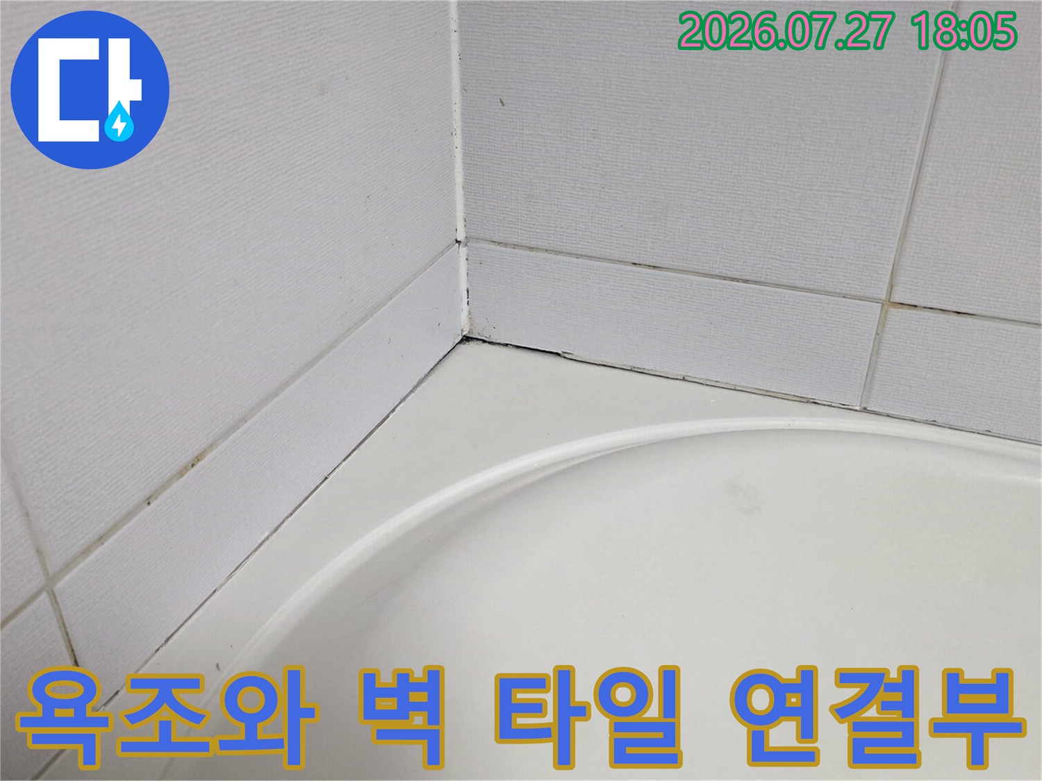 하얀색 욕조 상단과 벽면 타일의 경계선 부위를 근접 촬영한 사진