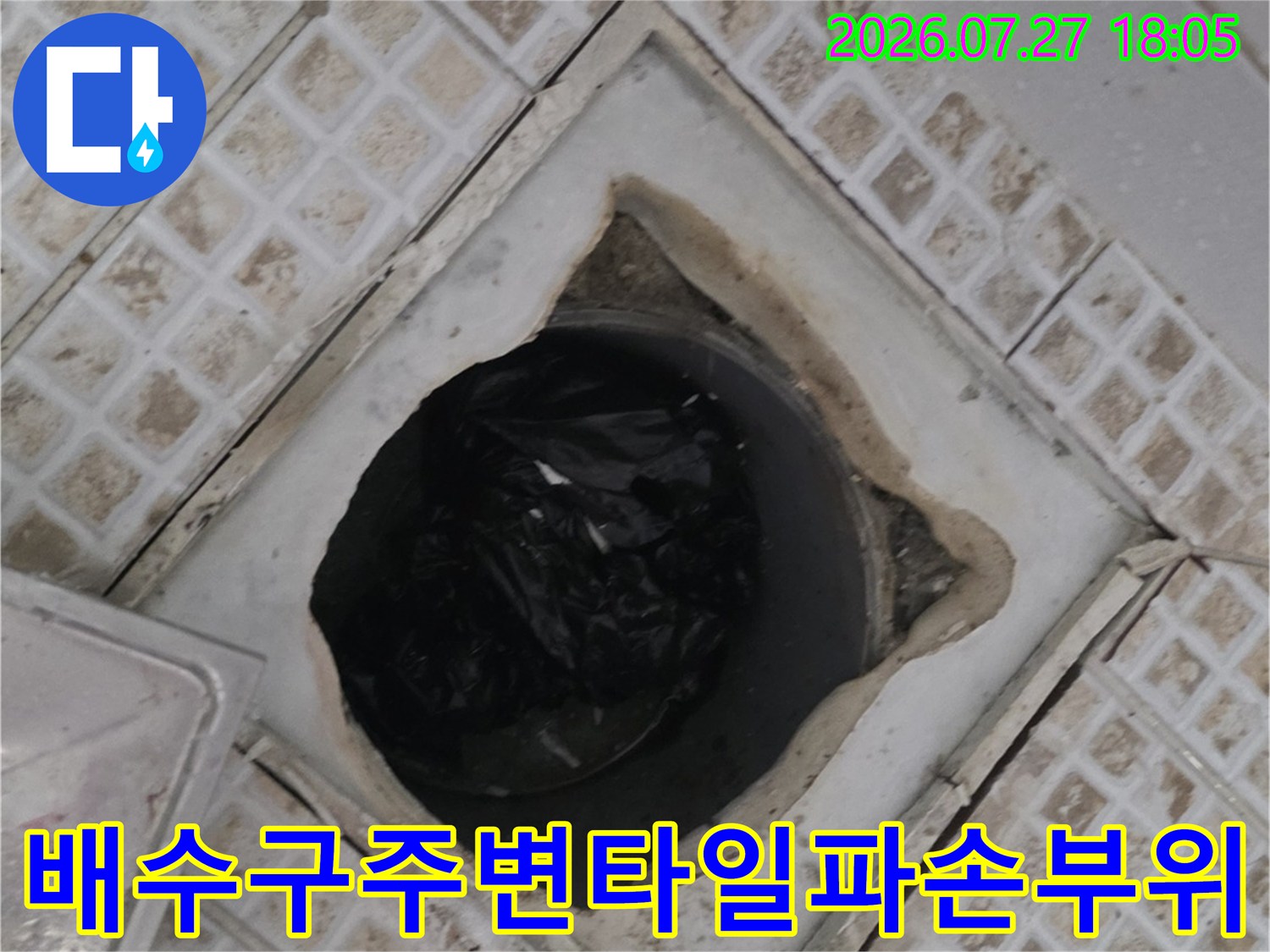 화장실 바닥 유가 주변의 타일이 떨어져 나가고 내부 공간이 노출된 사진