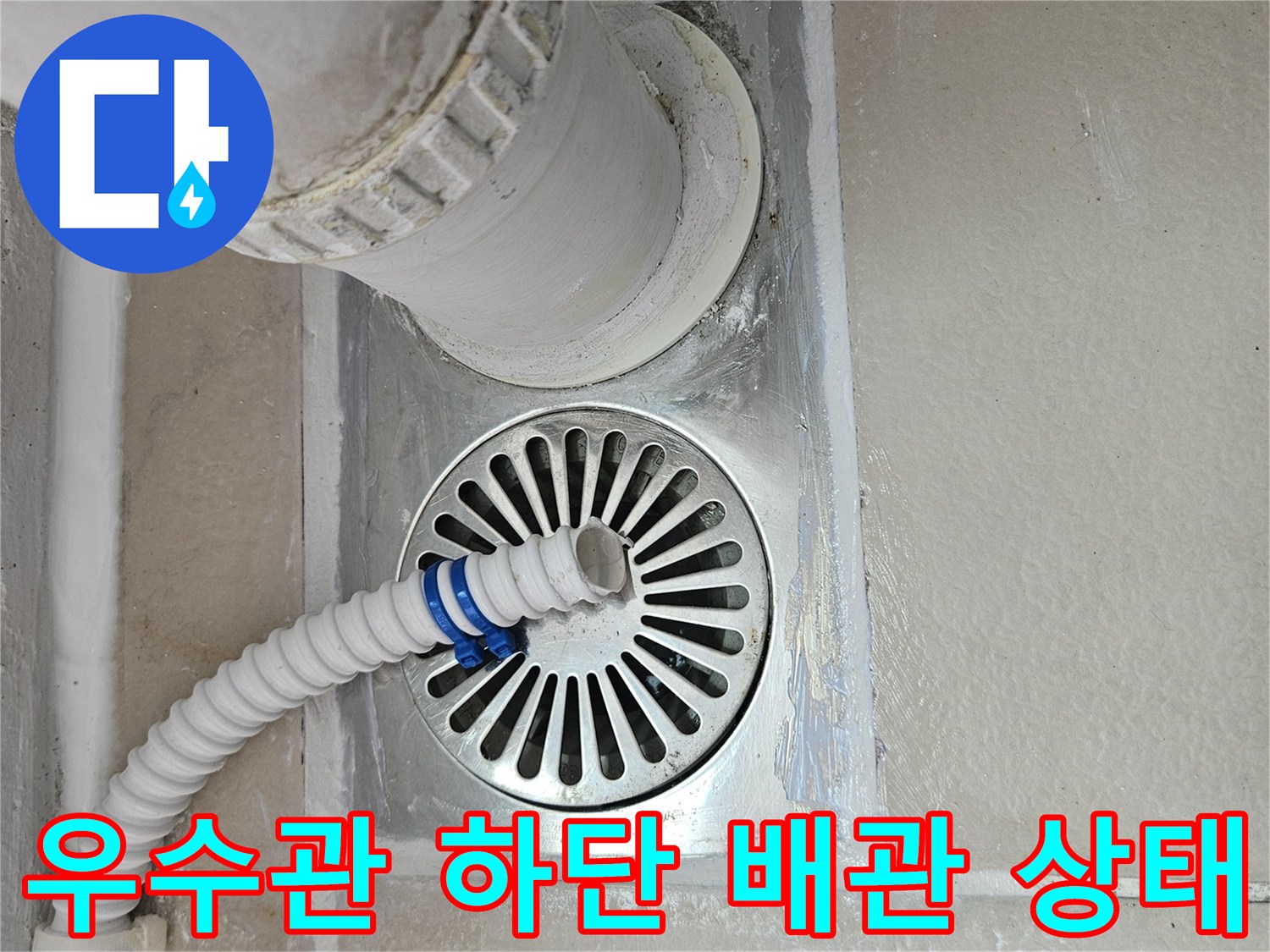 하얀색 우수관과 금속 재질의 배수구 유가 연결 부위입니다.