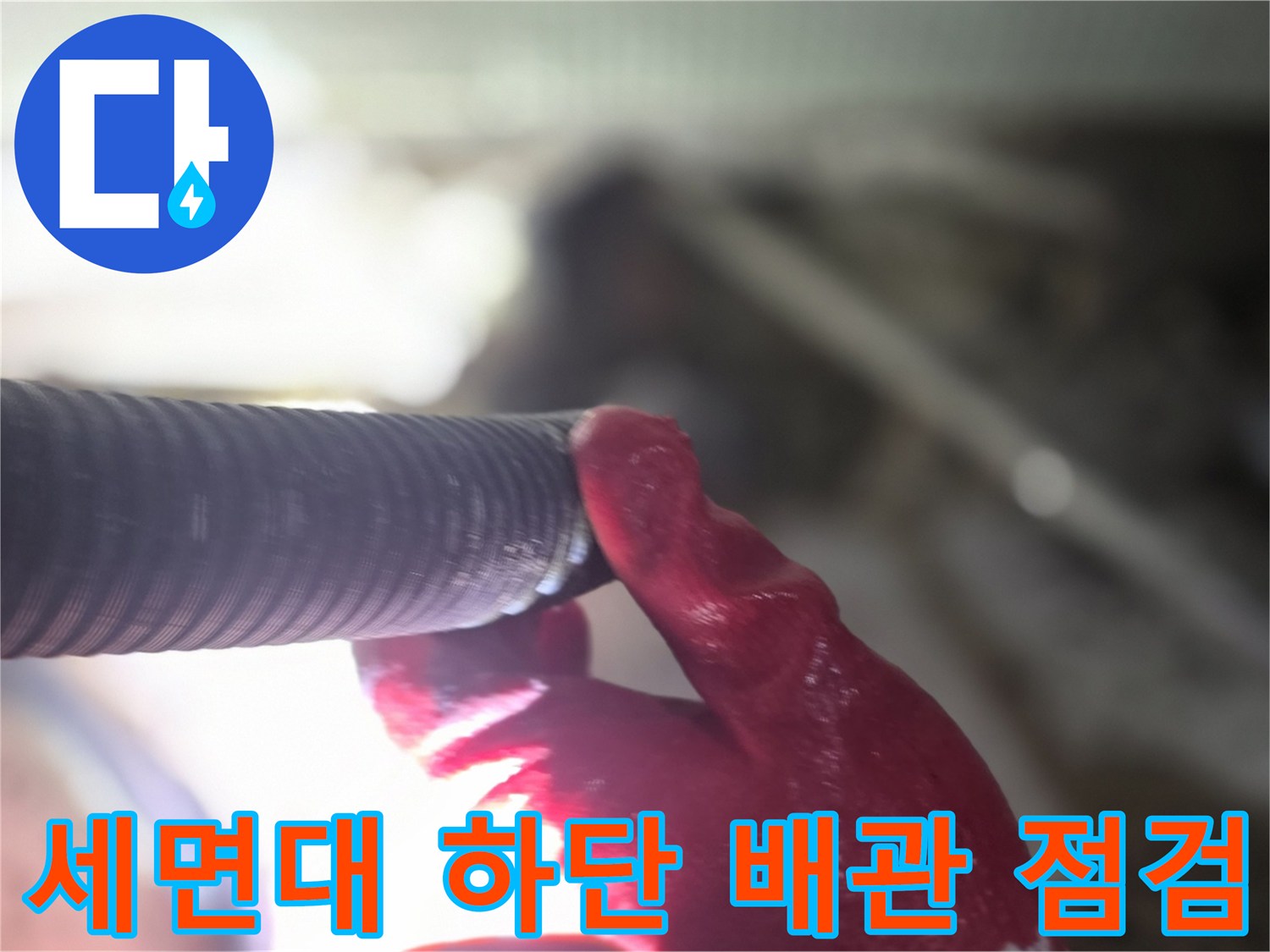 빨간 작업 장갑을 낀 손이 배관 부속을 잡고 있는 모습