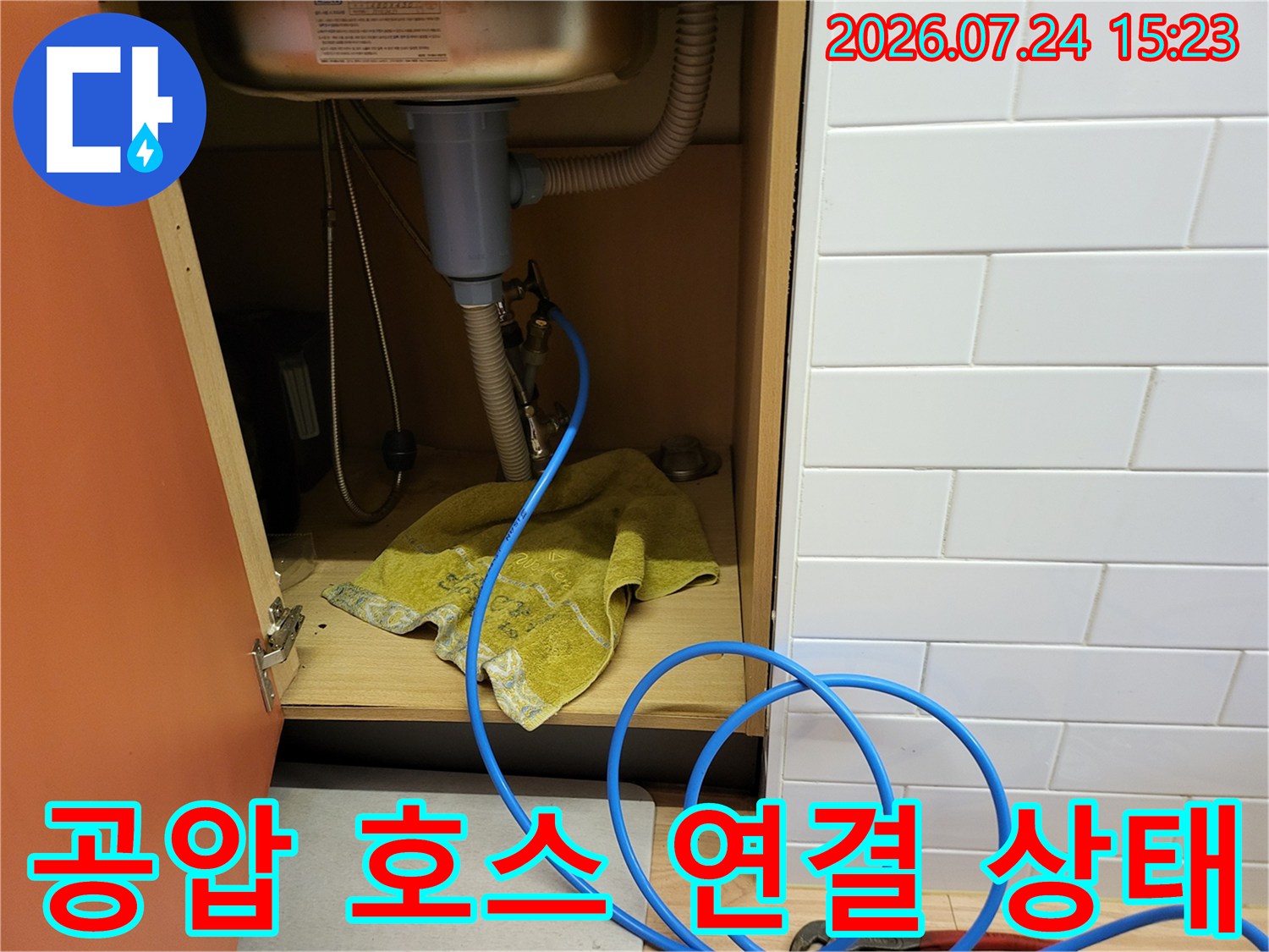 싱크대 하부의 회색 배수관 옆으로 파란색 공압 측정용 호스가 연결되어 있는 모습