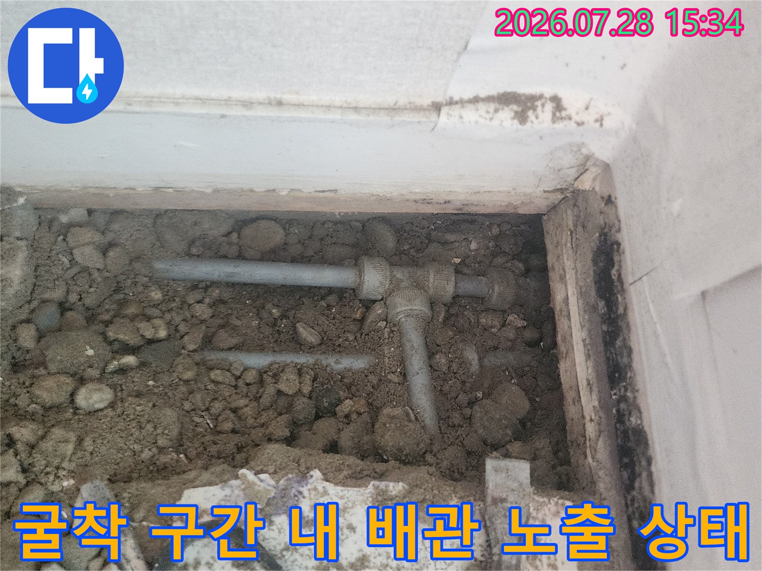 흙과 자갈이 섞인 지반에서 드러난 수도용 회색 배관