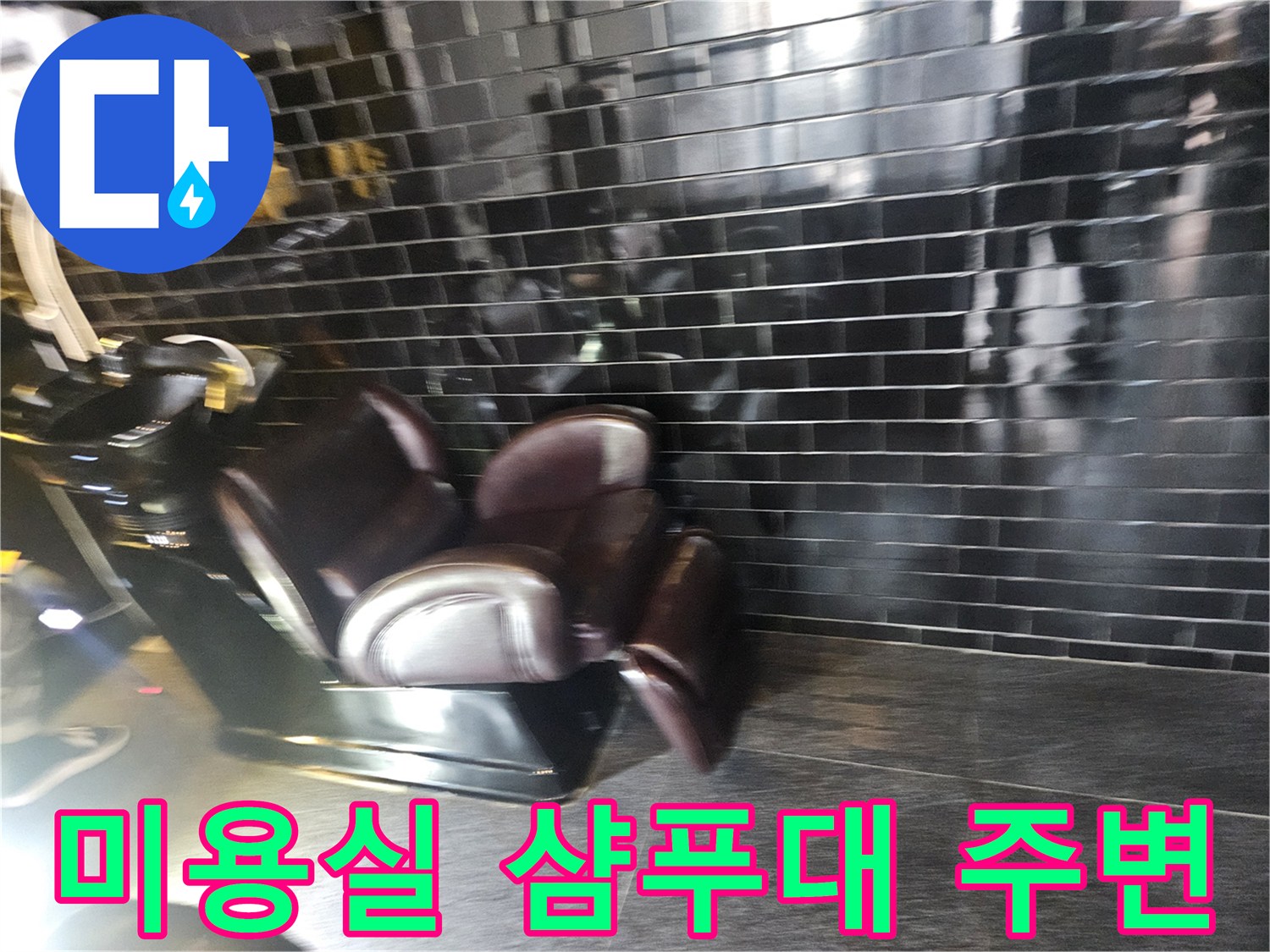 검은색 타일 벽면과 샴푸대가 위치한 미용실 내부 모습