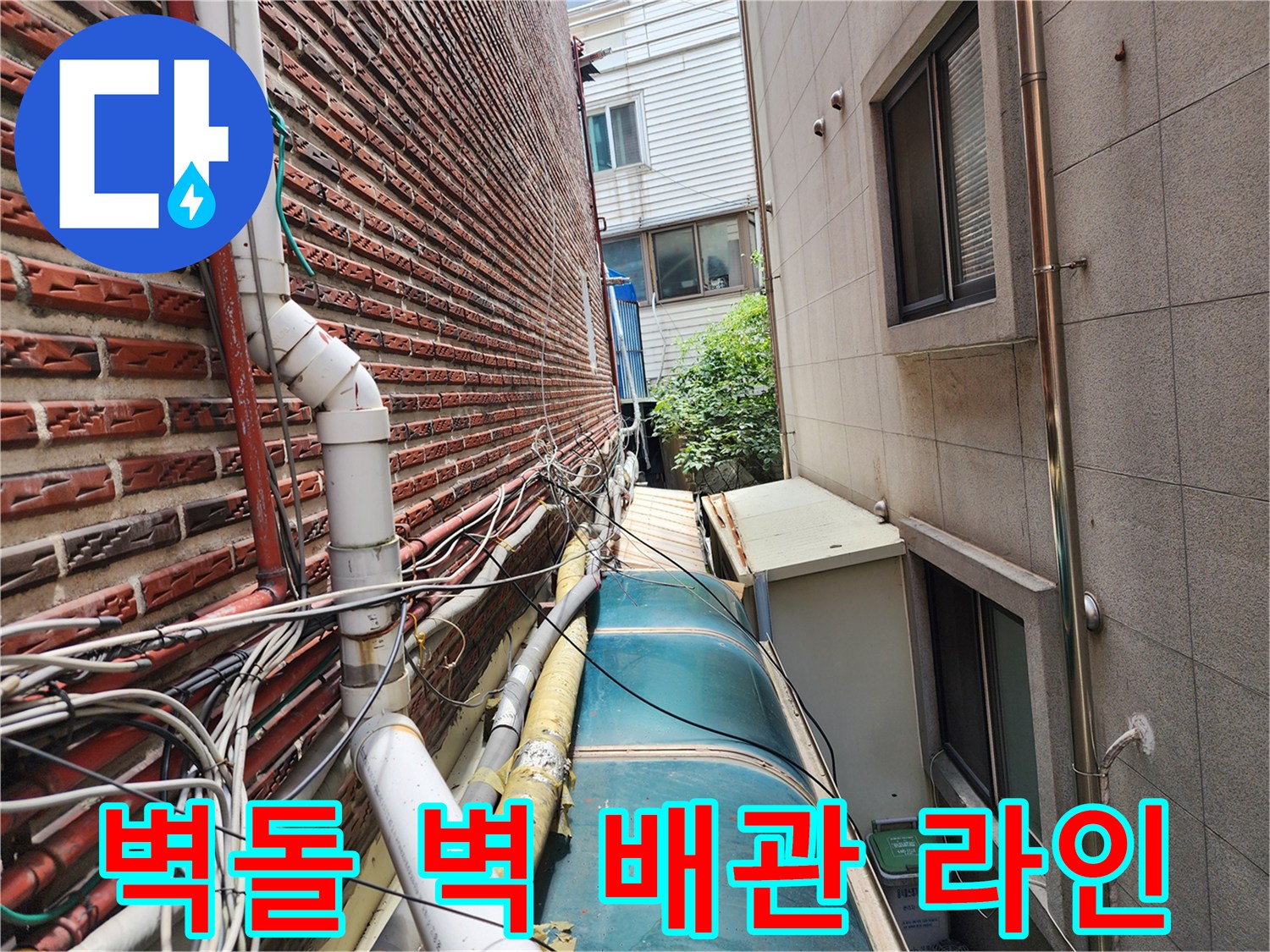 붉은 벽돌 외벽에 설치된 복잡한 외부 수도 배관 구조
