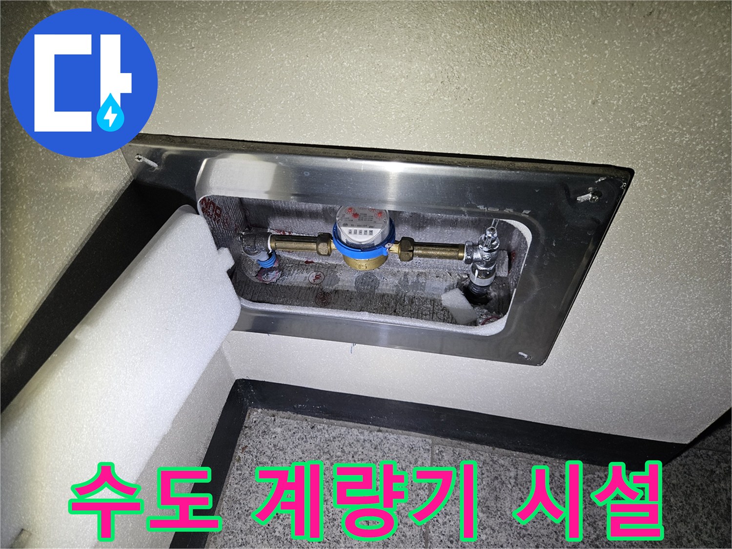 금속 점검판 안쪽에 위치한 수도 계량기와 밸브