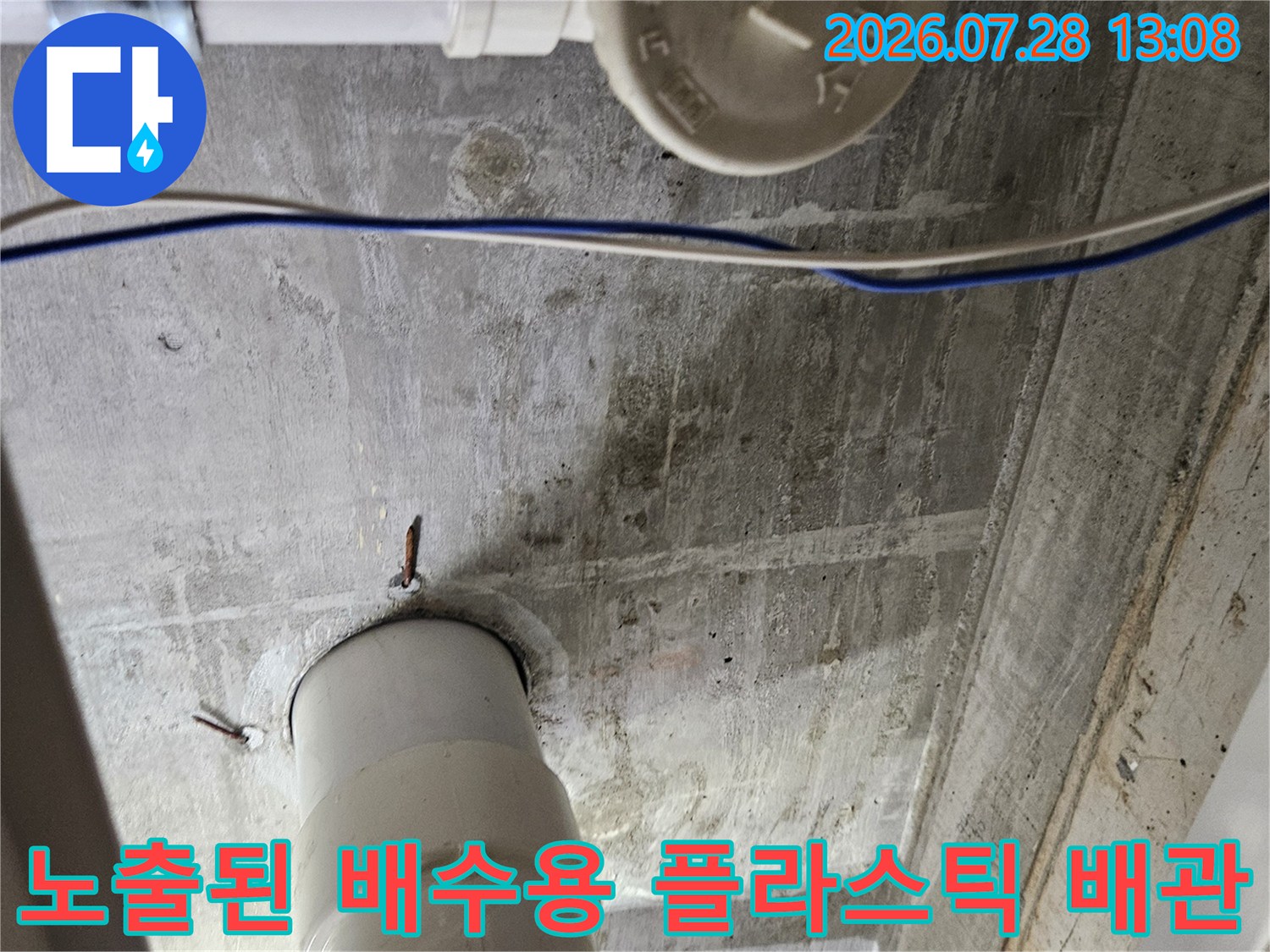 싱크대 하부 공간에 설치된 흰색 플라스틱 재질의 굴곡진 배수 배관을 촬영한 이미지