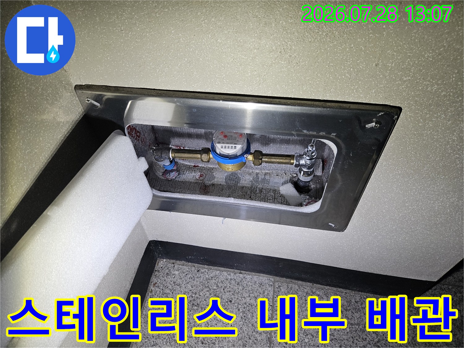 주방 하부 공간 내부에 노출된 스테인리스 마감재와 연결된 배관들