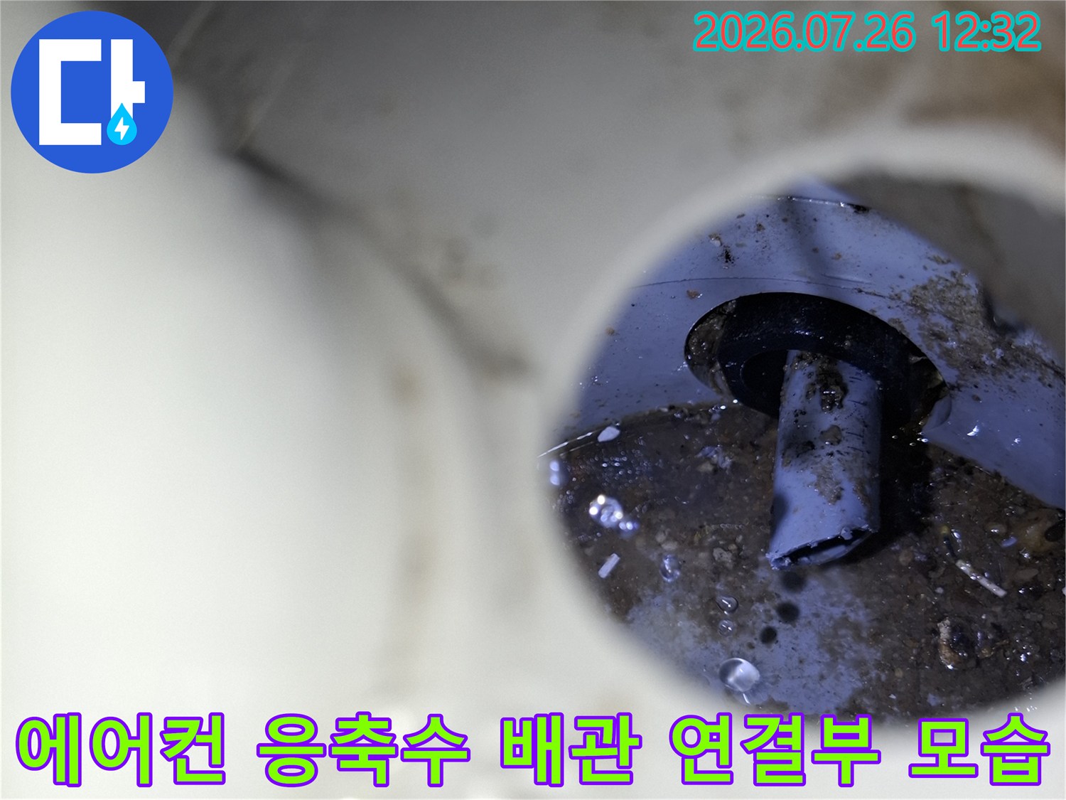 흰색 플라스틱 배관 슬리브 내부로 검은색 에어컨 응축수 호스가 연결된 모습
