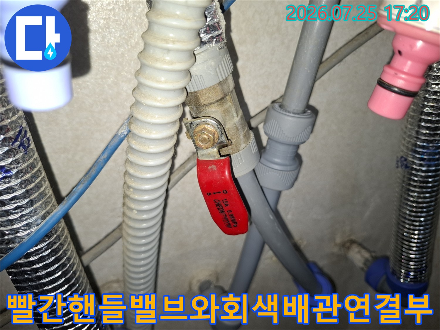 회색 배관과 적색 핸들이 달린 밸브-파란색 커넥터가 연결된 누수 지점 모습