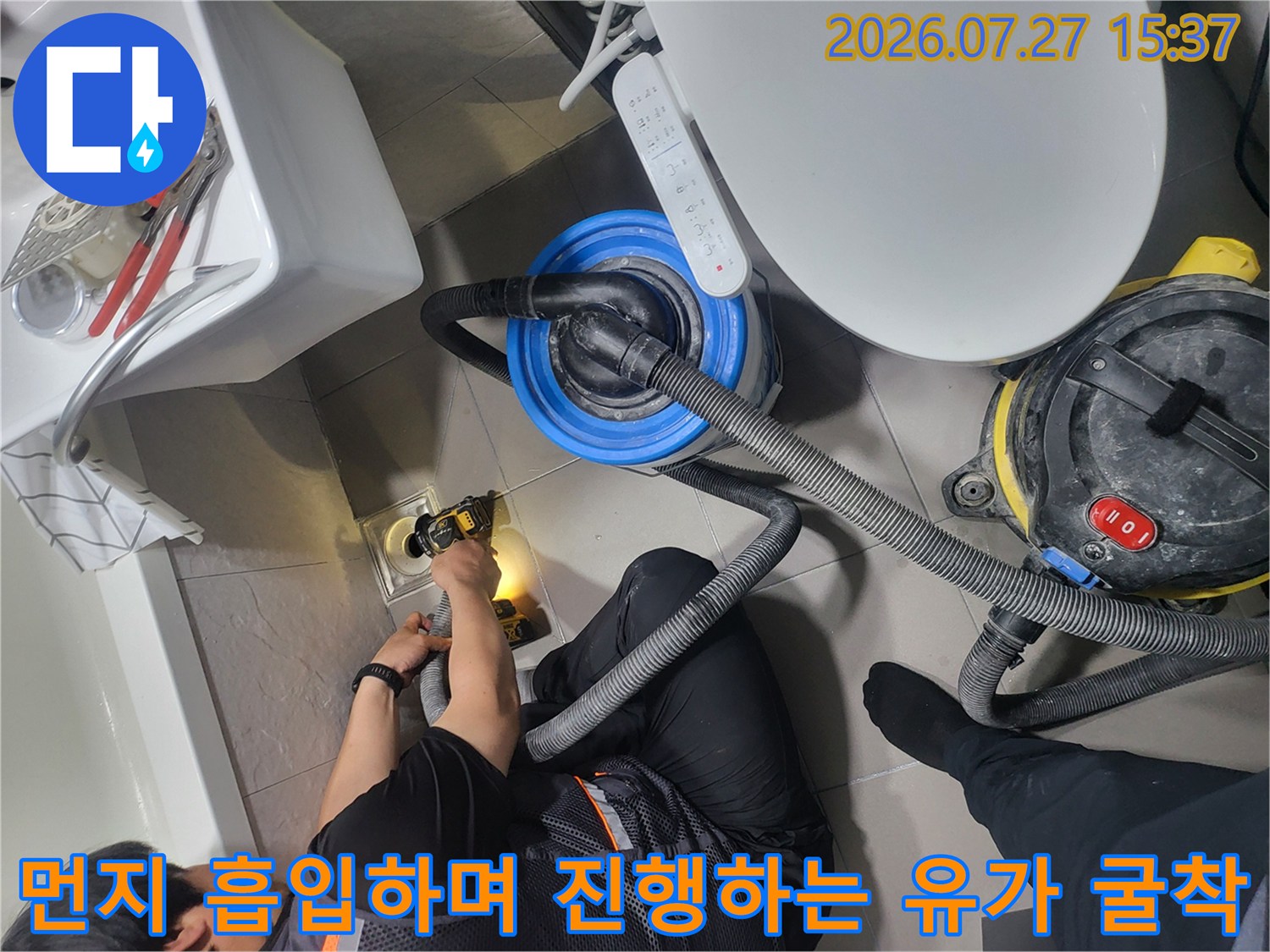 강력한 집진 장비를 연결하여 화장실 바닥의 배수구 부분을 조심스럽게 파내고 있는 현장 사진