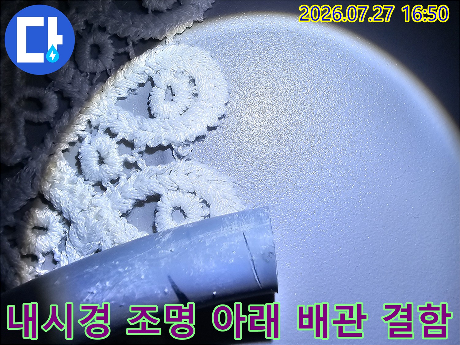 어두운 천장 공간에서 내시경 라이트로 비춘 손상된 배관의 모습