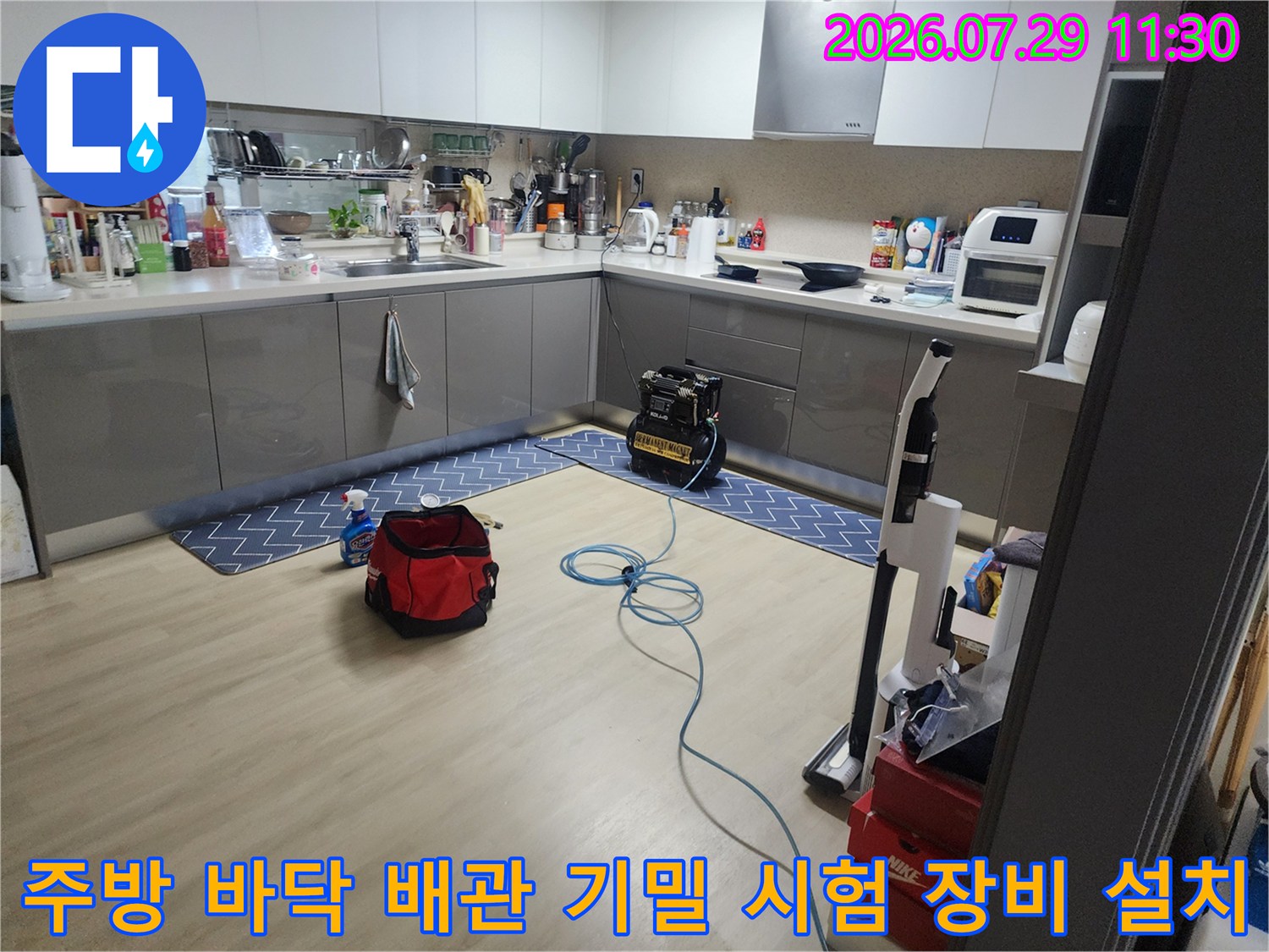 파란색 호스와 노란색 측정기기가 연결된 주방 누수 진찰 장면