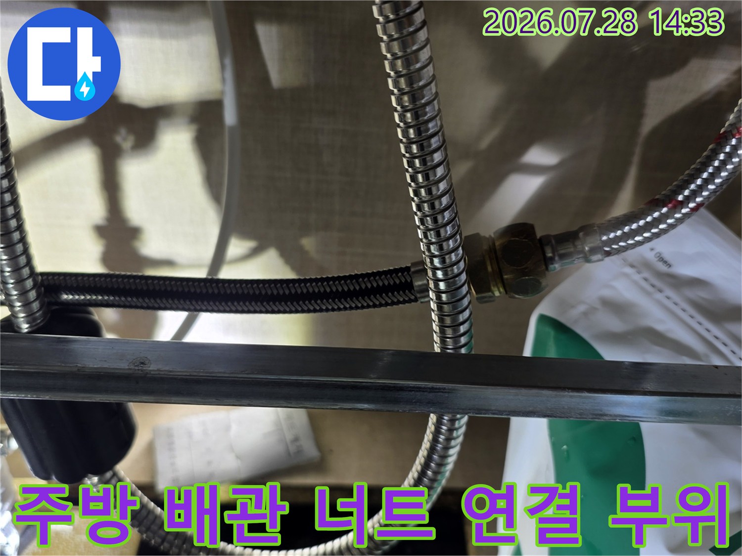 스테인리스 소재의 주름관들이 서로 연결되어 있는 싱크대 하부 모습