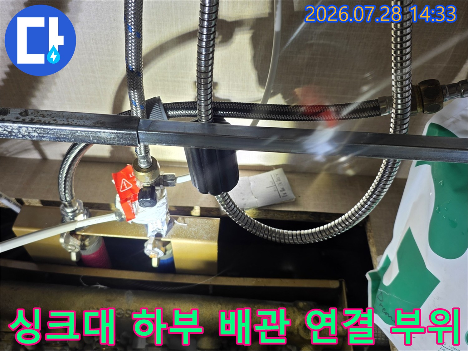 싱크대 아래 스테인리스 주름관과 분배기가 연결된 배관 시스템 모습