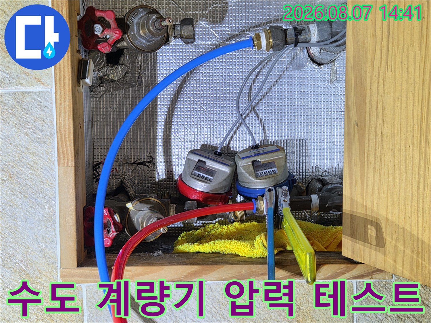 수도 계량기에 연결된 파란색과 빨간색의 배관 테스트 호스 상세