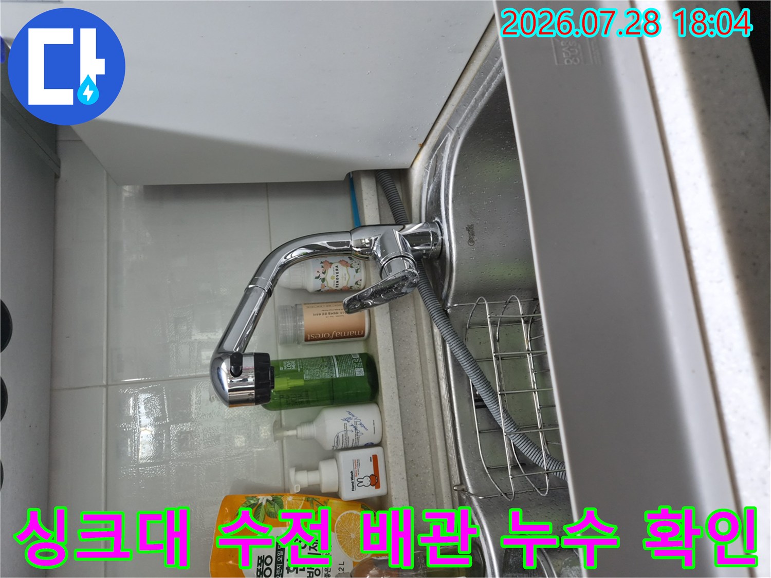 싱크대 하부에서 노출된 수전과 연결된 호스 및 배관의 상태를 점검하는 모습