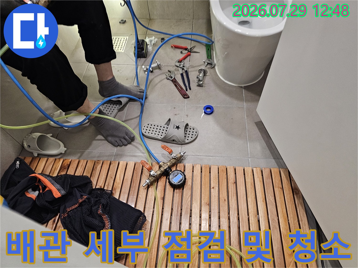 전문 작업자가 배관 노즐과 장비를 연결해 베란다 하단 배수관을 정비하는 장면