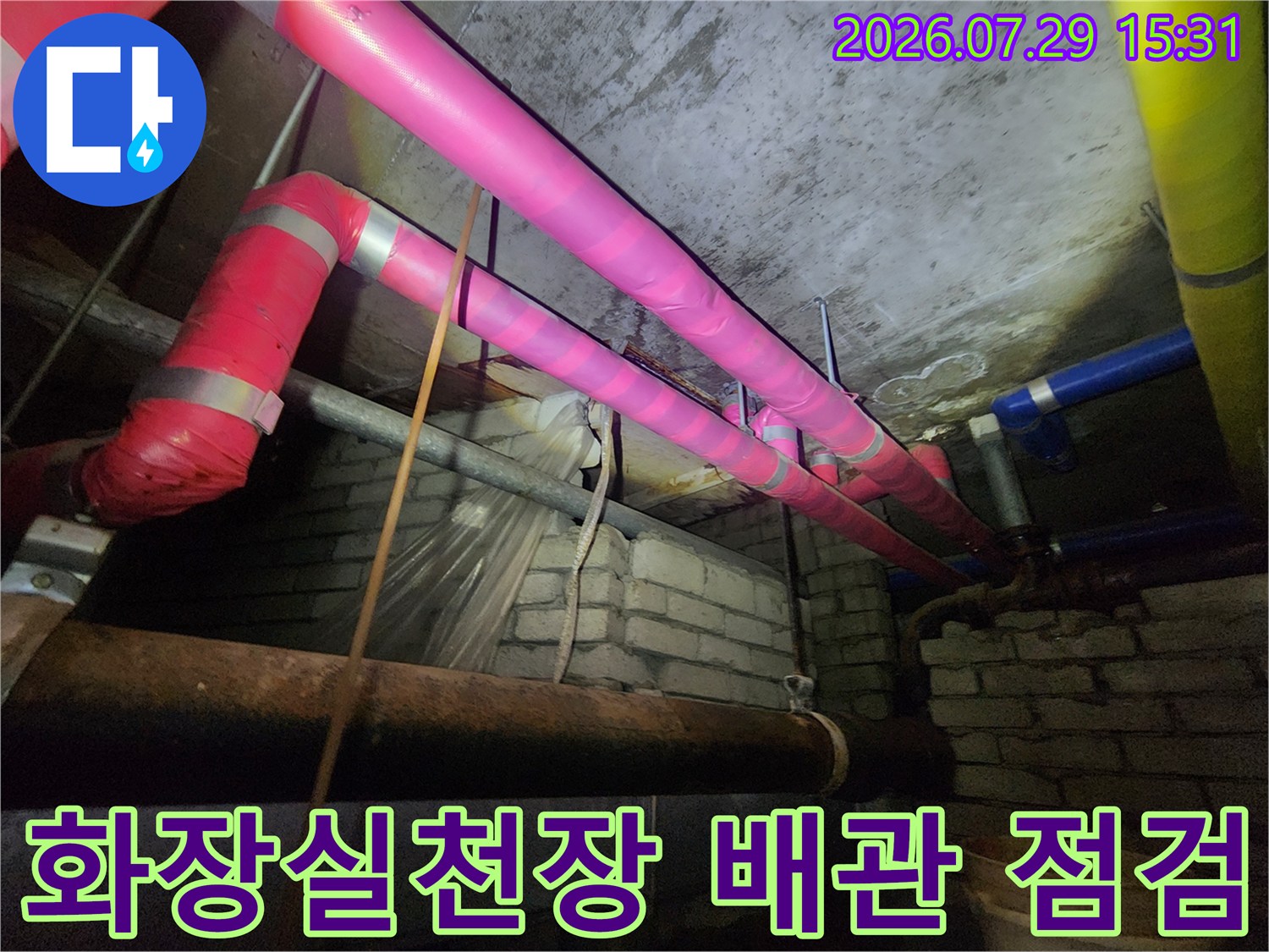 분홍색과 파란색 보온재로 감싸진 천장 배관 점검 모습