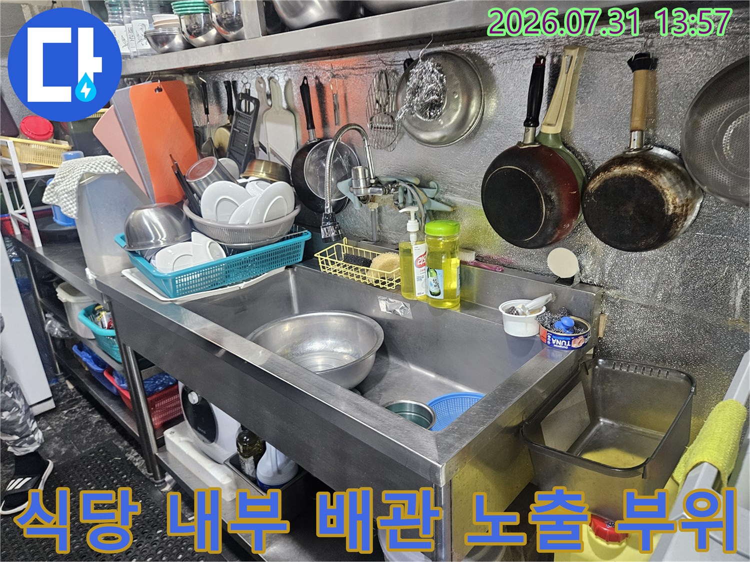 조리 도구와 주변기기가 배치된 환경 내의 수도 배관 점검 모습