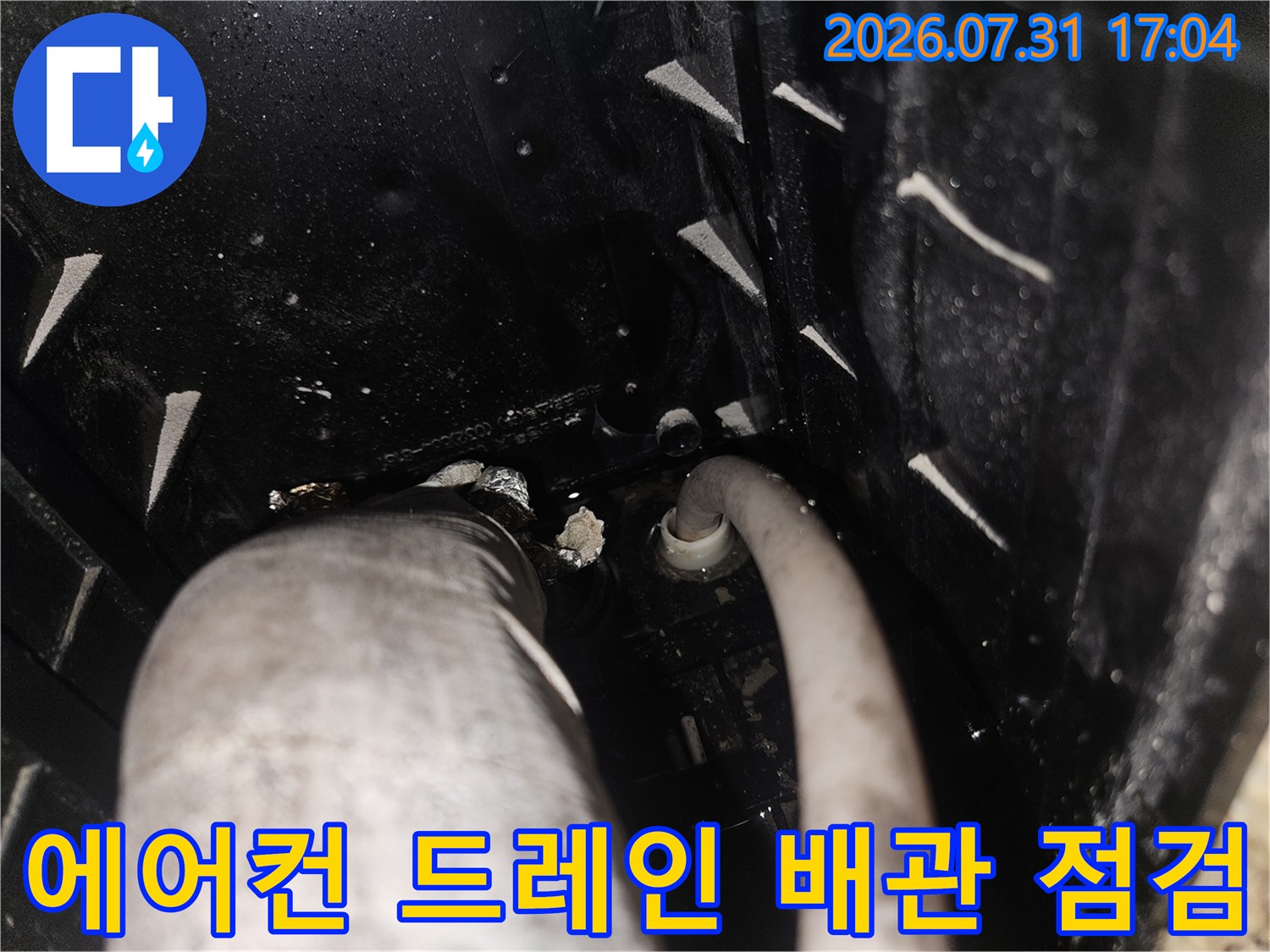 에어컨 응축수 배출용 드레인 배관의 연결 부위를 정밀하게 점검하는 모습