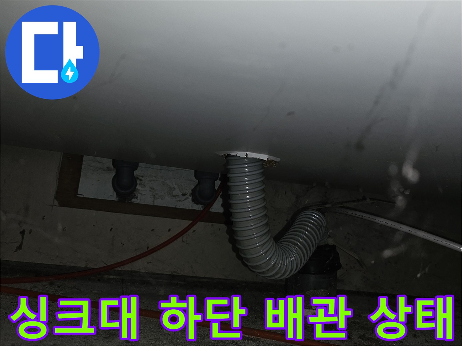 주방 싱크대 아래-벽면과 연결된 회색 주름형 배관 노출 모습