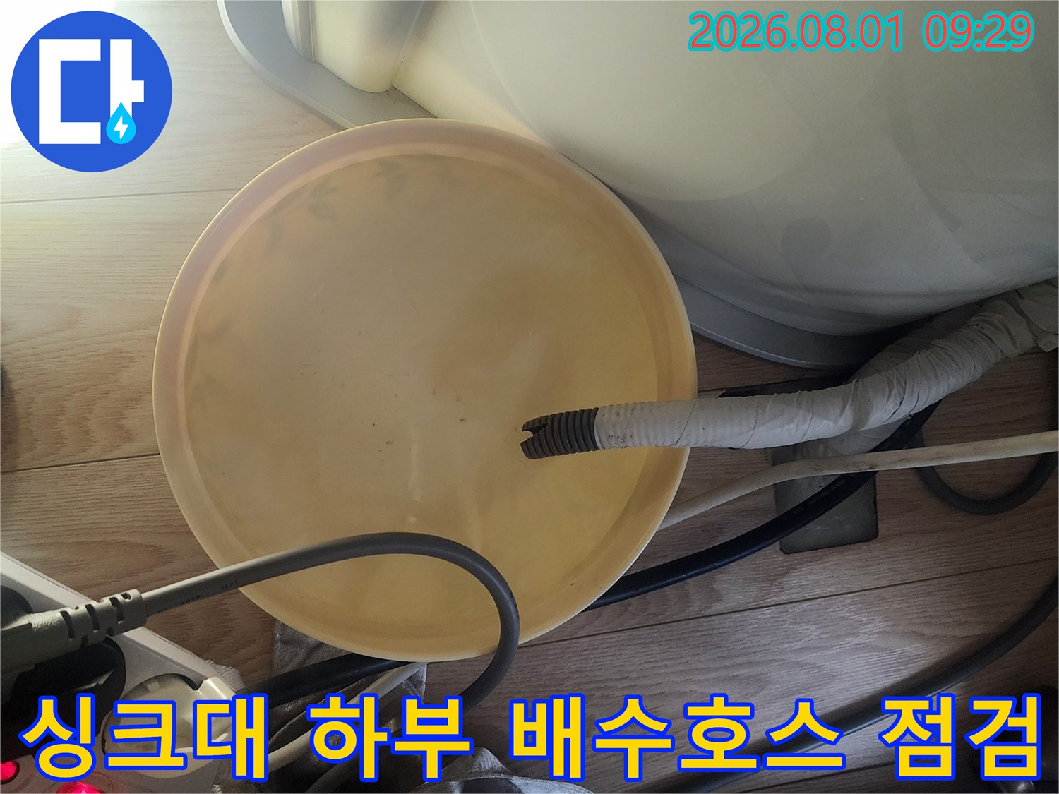 싱크대 아래에 설치된 노란색 배수 덮개와 연결된 배수 호스 구조물