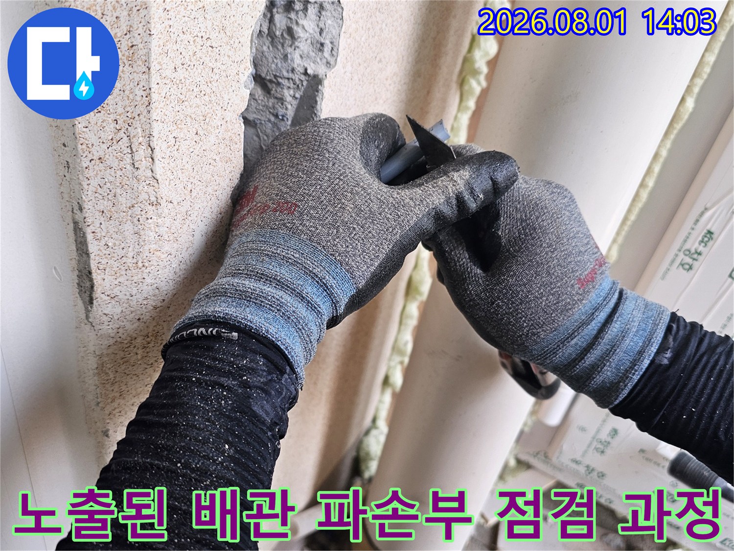 작업자가 세탁실 벽면을 뚫고 나온 누수 배관의 상태를 확인하는 장면