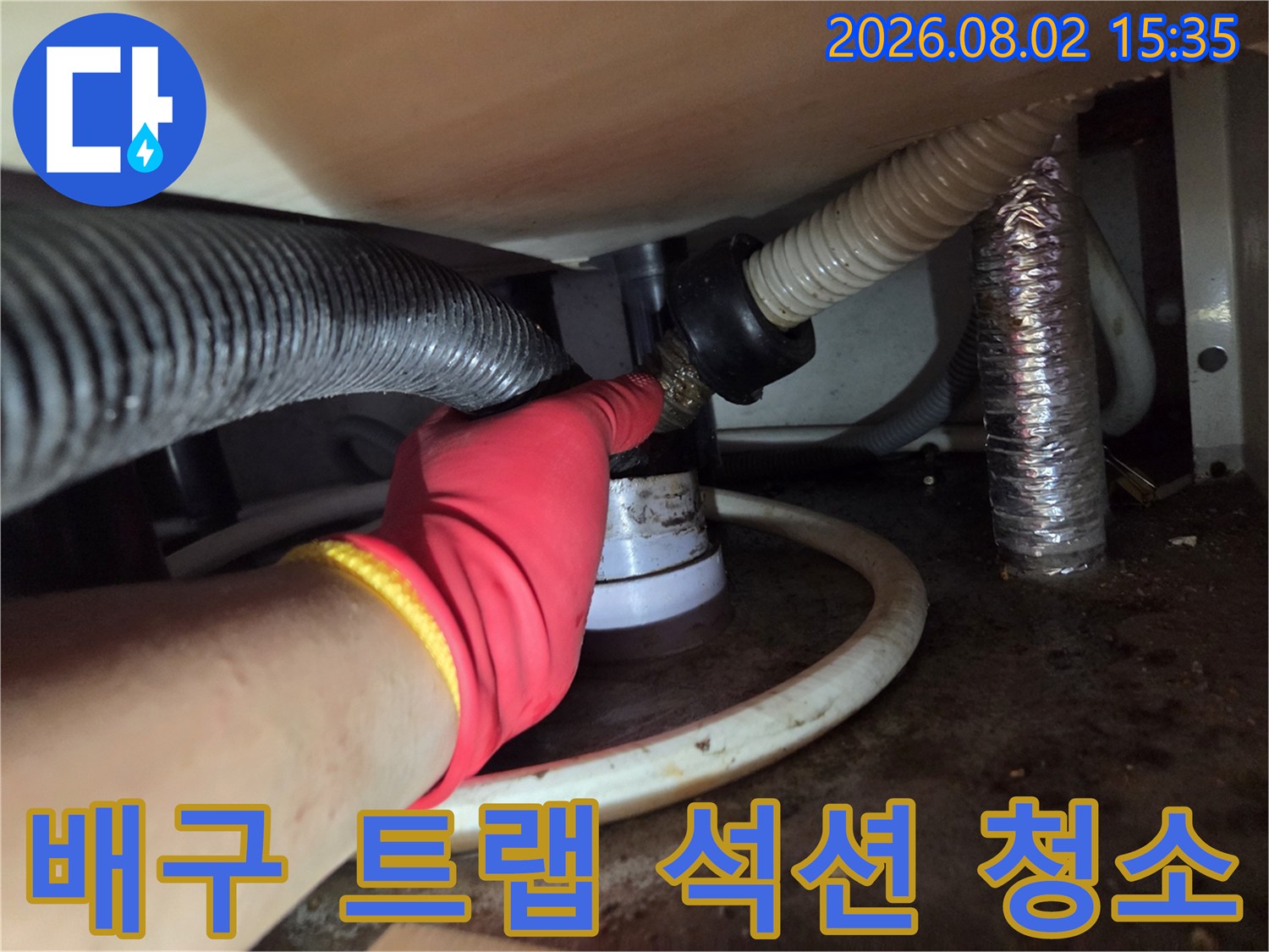 부드러운 곡선을 그리는 싱크대 배수 호스 사이로 석션 장비를 연결하여 이물질을 제거하는 모습.