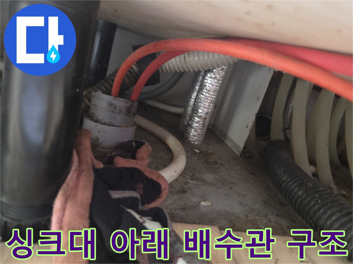 싱크대 하단 굵은 배관과 주황색 호스가 연결된 모습