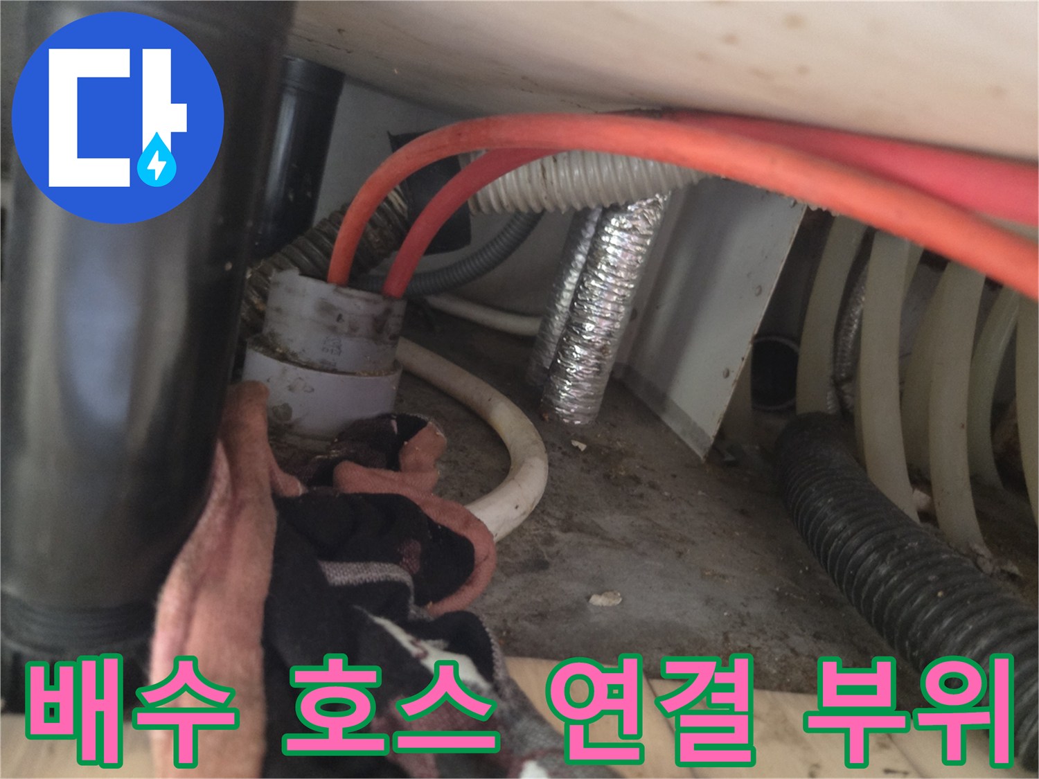 주방 하부 배관-복잡하게 얽힌 주름관과 배수 호스의 연결 모습