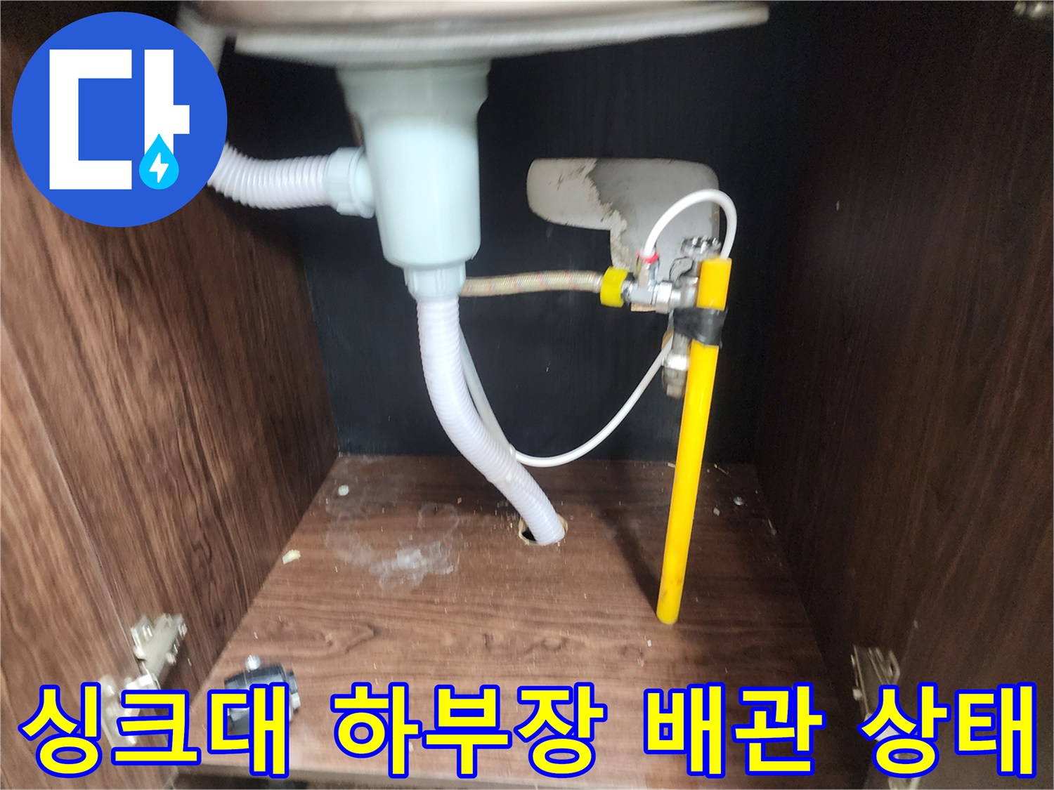 천안 동남구 싱크대 하부장 내부의 노후된 배수 호스와 수도 밸브 모습