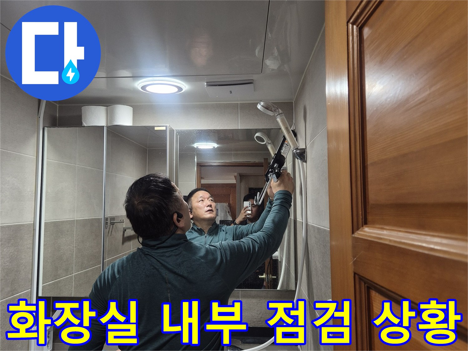 세면대와 거울이 있는 욕실에서 누수 부위를 찾는 작업자