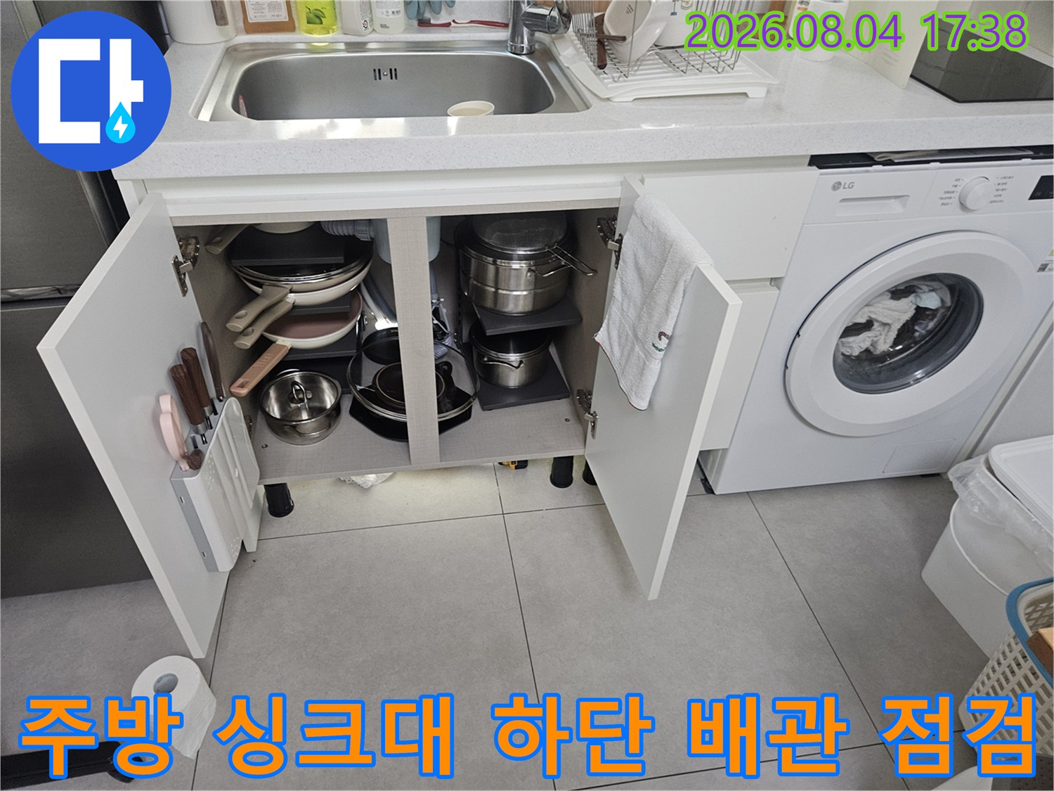 싱크대 아래에 위치한 냄비들과 노출된 수도 배관 라인