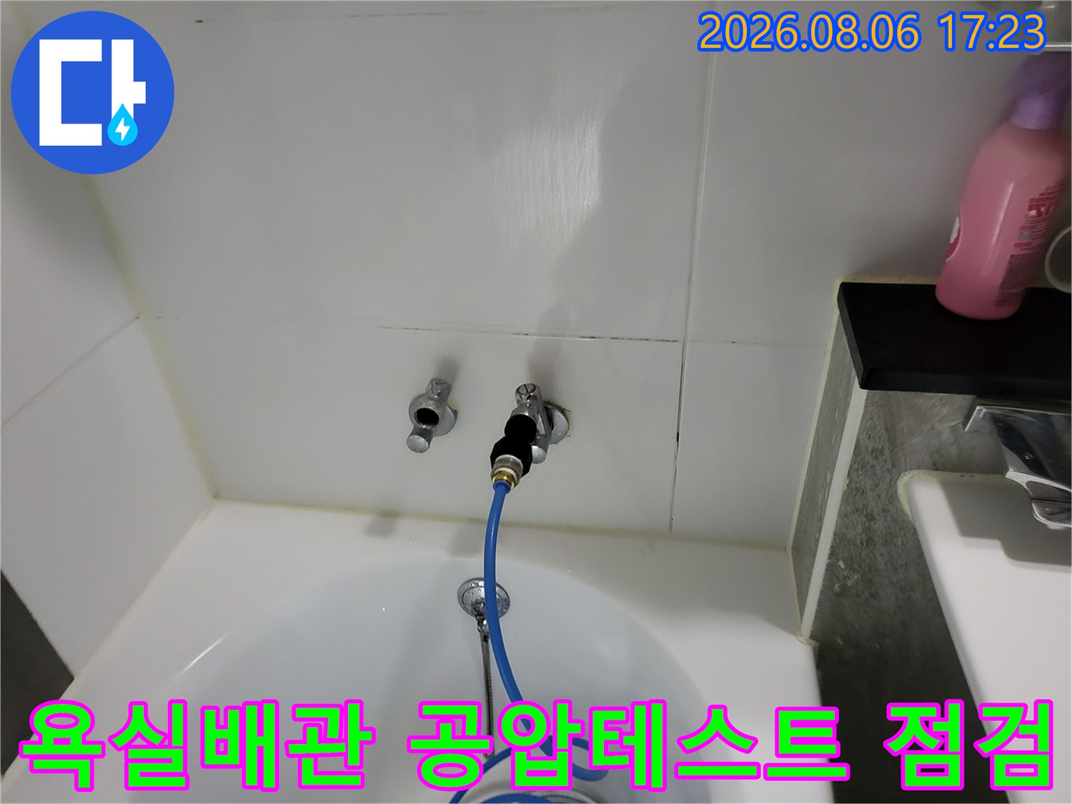 욕실 세면대 위 배관에 연결된 파란색 호스를 이용해 공압 테스트를 진행하는 모습