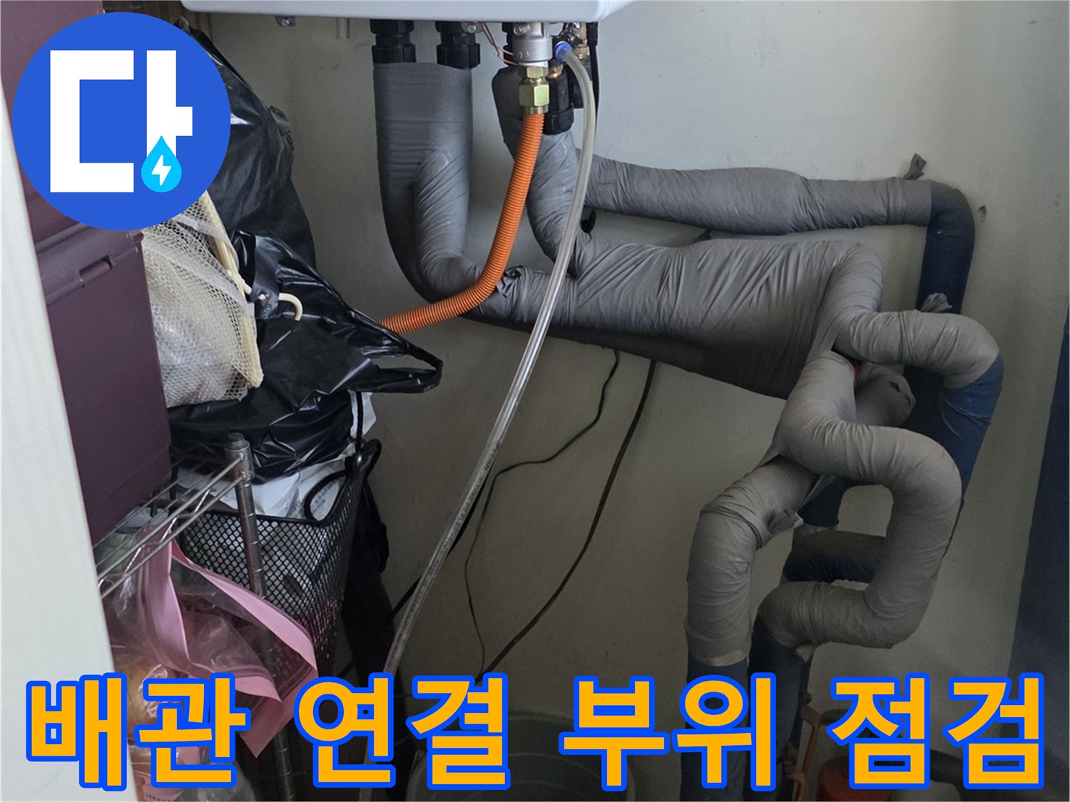 보일러 하단의 주황색 호스와 회색 보온재 배관의 상세 근접 사진