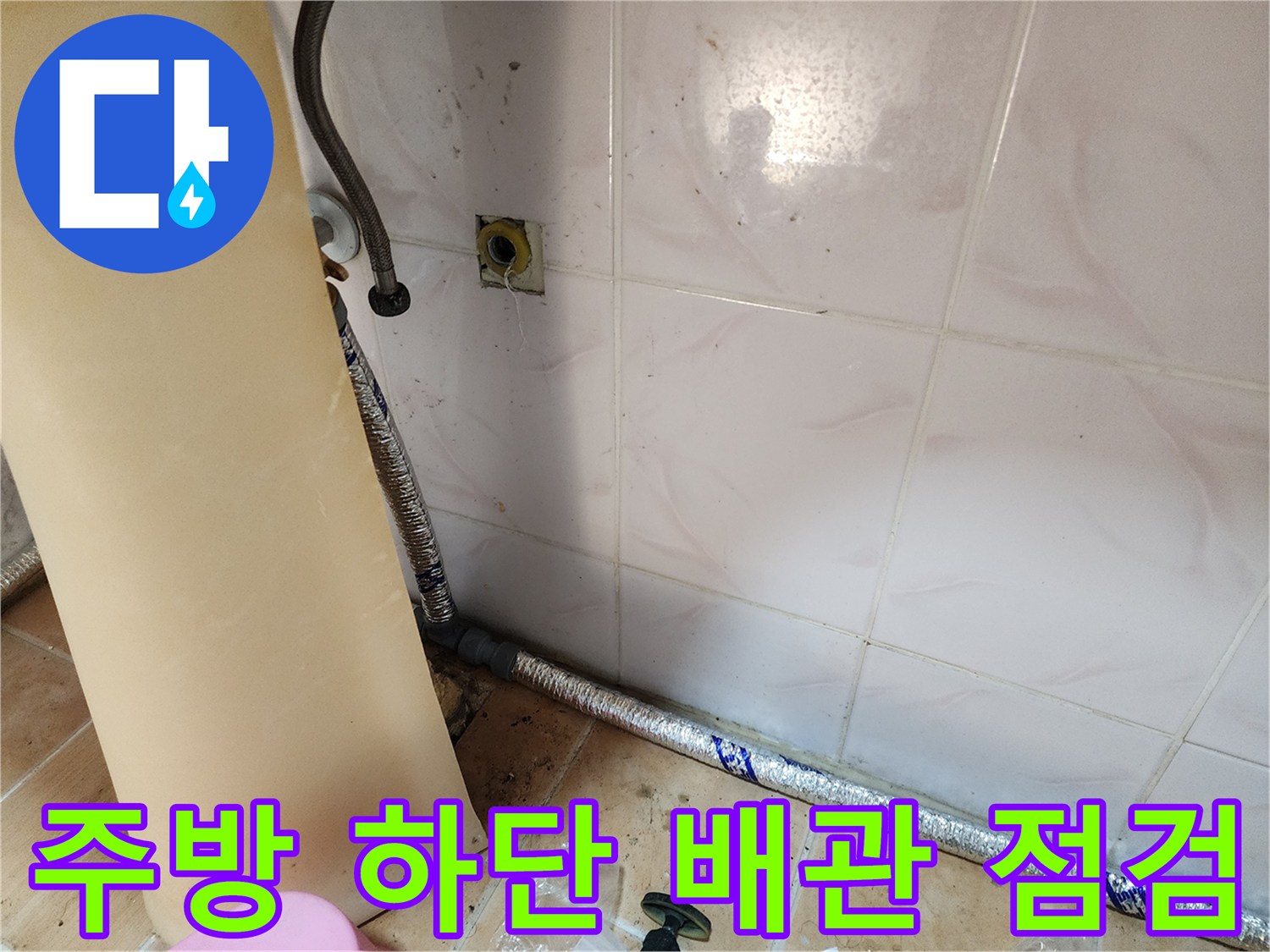 싱크대 밑 은색 보온재로 감싸진 배관의 타일 벽 접촉부