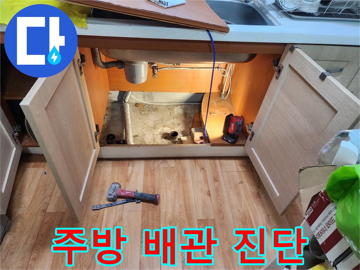 싱크대 하부장 내부의 배관 구조와 점검용 장비가 놓인 모습
