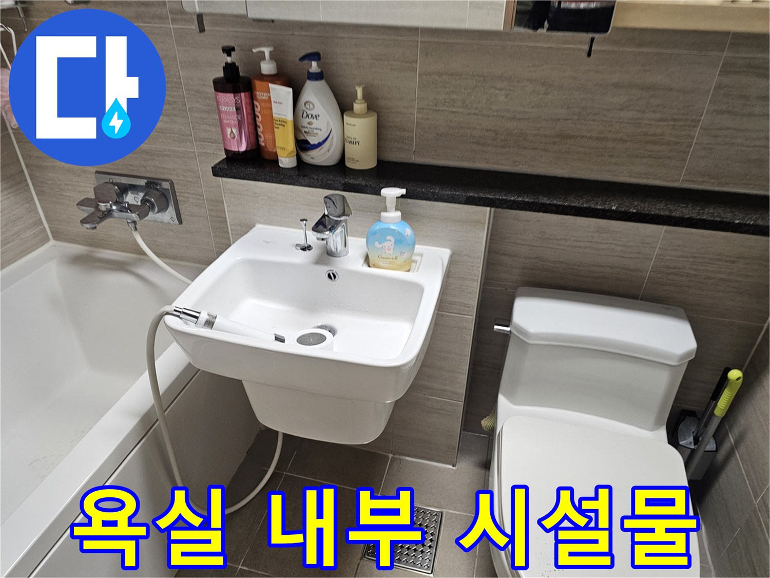 세면대와 변기 그리고 선반 위에 놓인 세정제들이 보이는 화장실 전경입니다.