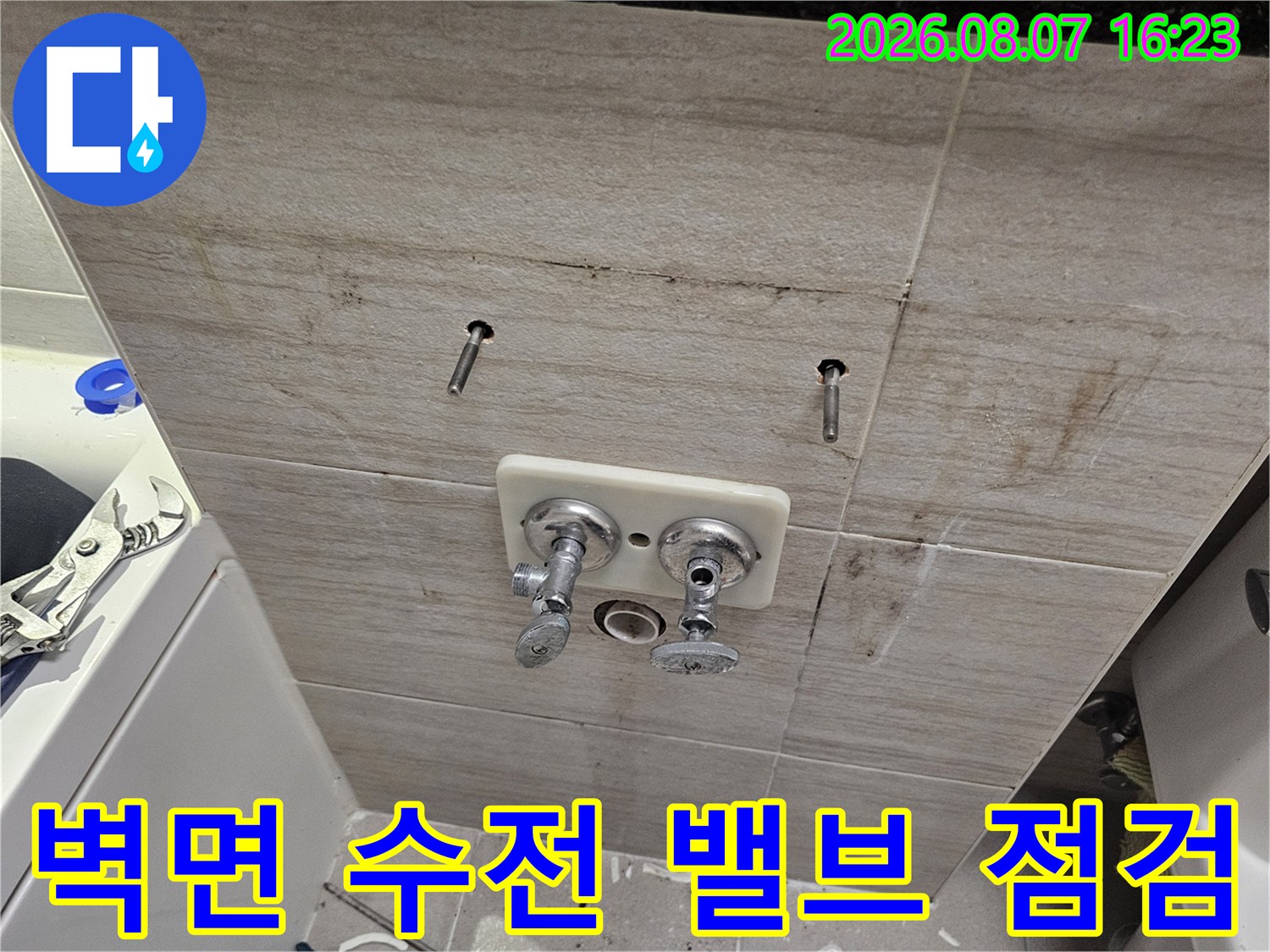 화장실 벽면에 노출된 세면대 수전과 배관 부품 사진입니다.
