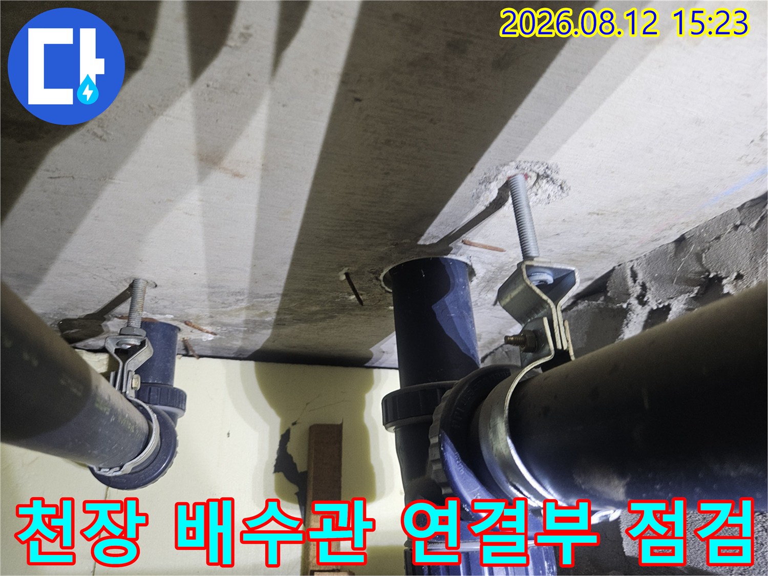 천장에 매달려 있는 검은색 배수 파이프와 고정용 금속 브라켓 사진