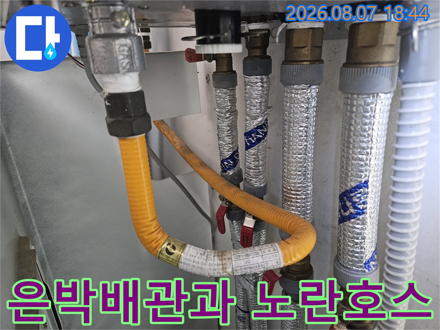 은박 보온재로 감싸진 배관과 노란색 호스가 연결된 설비 내부 모습
